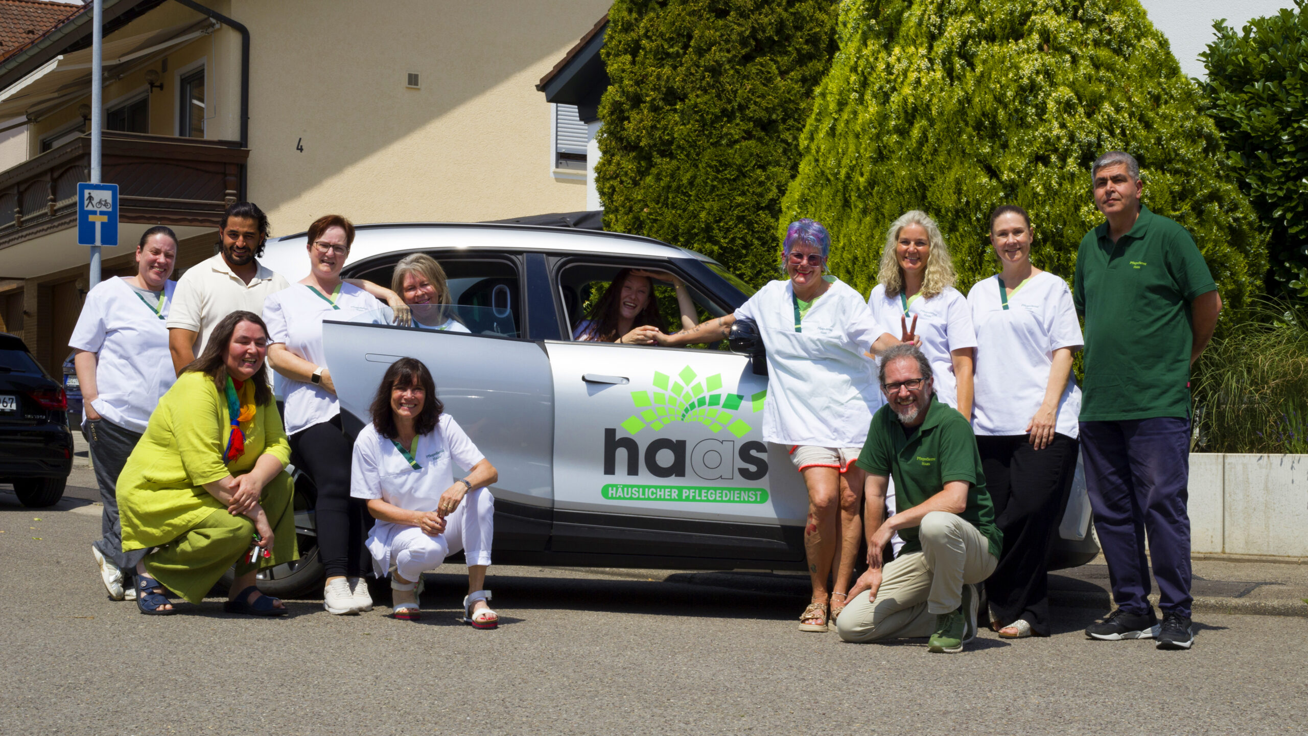Das Haas Pflege Team steht vor dem Haas Pflegeauto